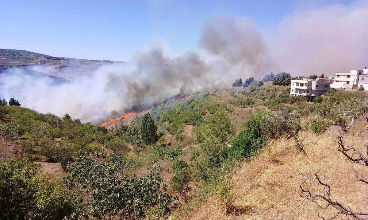 A wildfire burns near buildings in the countryside, causing some residents to evacuate, in Al-Marana village, Homs, Syria on July 18, 2023 in this handout image. (Reuters)