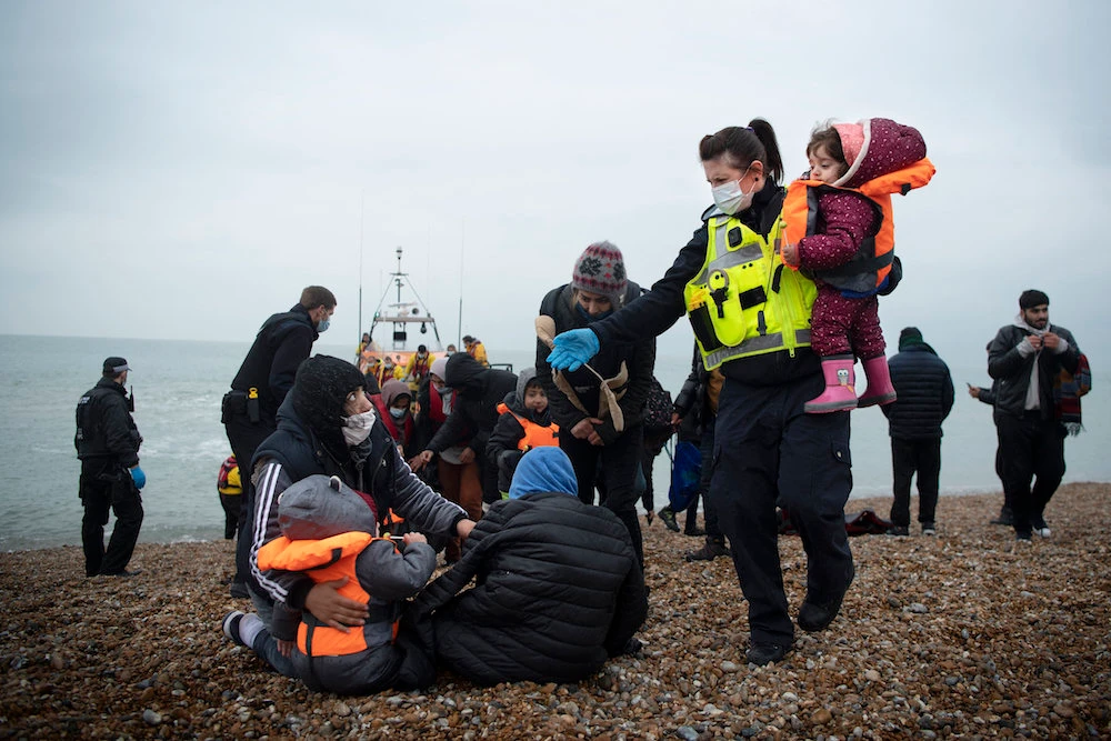 A member of the UK Border Force (R) helps child migrants on a beach in Dungeness, on the south-east coast of England, on November 24, 2021 after being rescued while crossing the English Channel. (AFP)