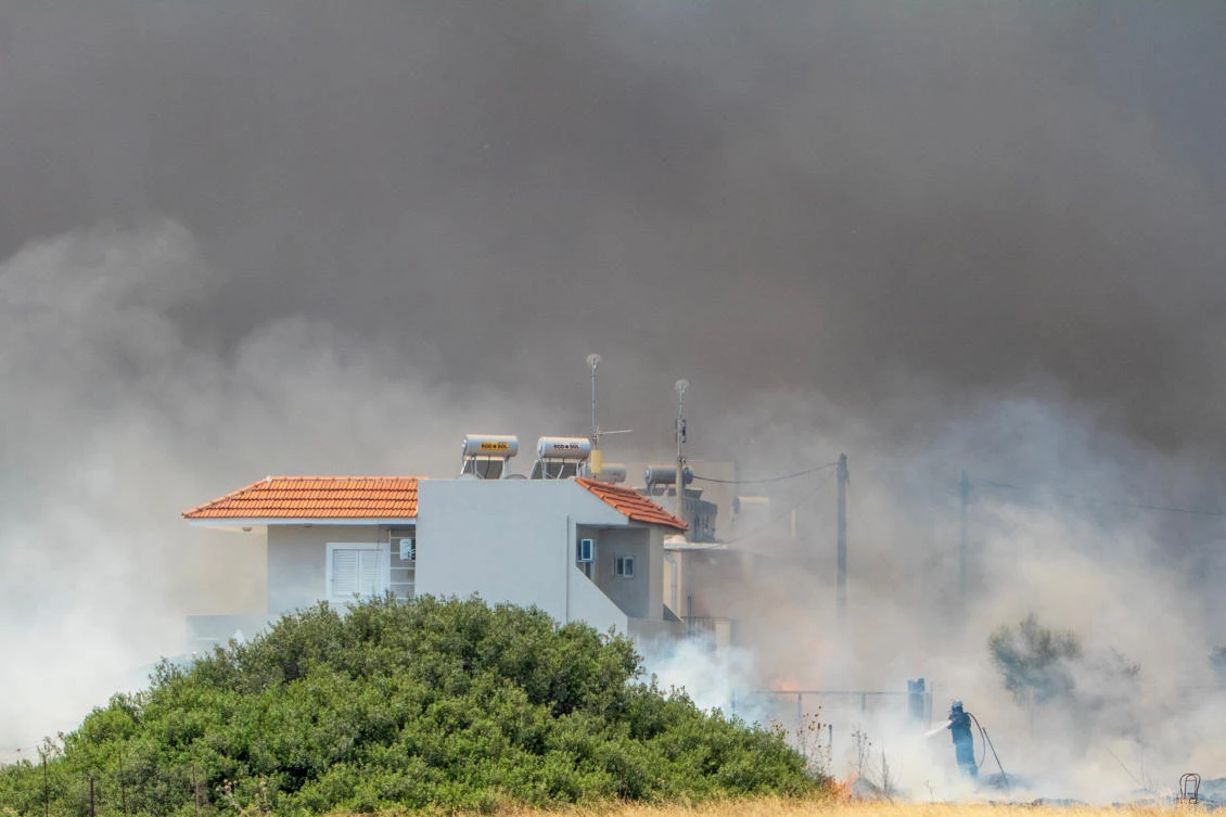 A firefighter tries to extinguish a fire, as a wildfire burns in the village of Kiotari, on the island of Rhodes, Greece, July 24, 2023. (REUTERS)