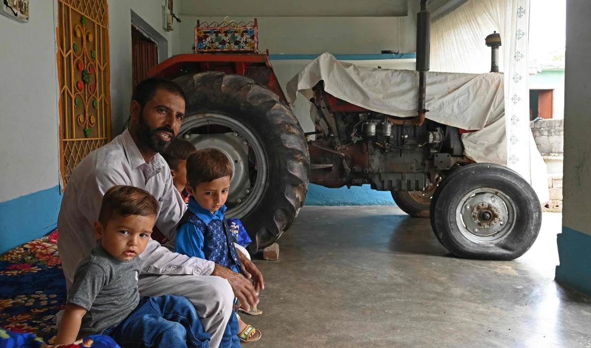 In this picture taken on July 18, 2023, Pakistani worker Muhammad Naeem Butt sits with his children at his home in Khuiratta. (AFP)