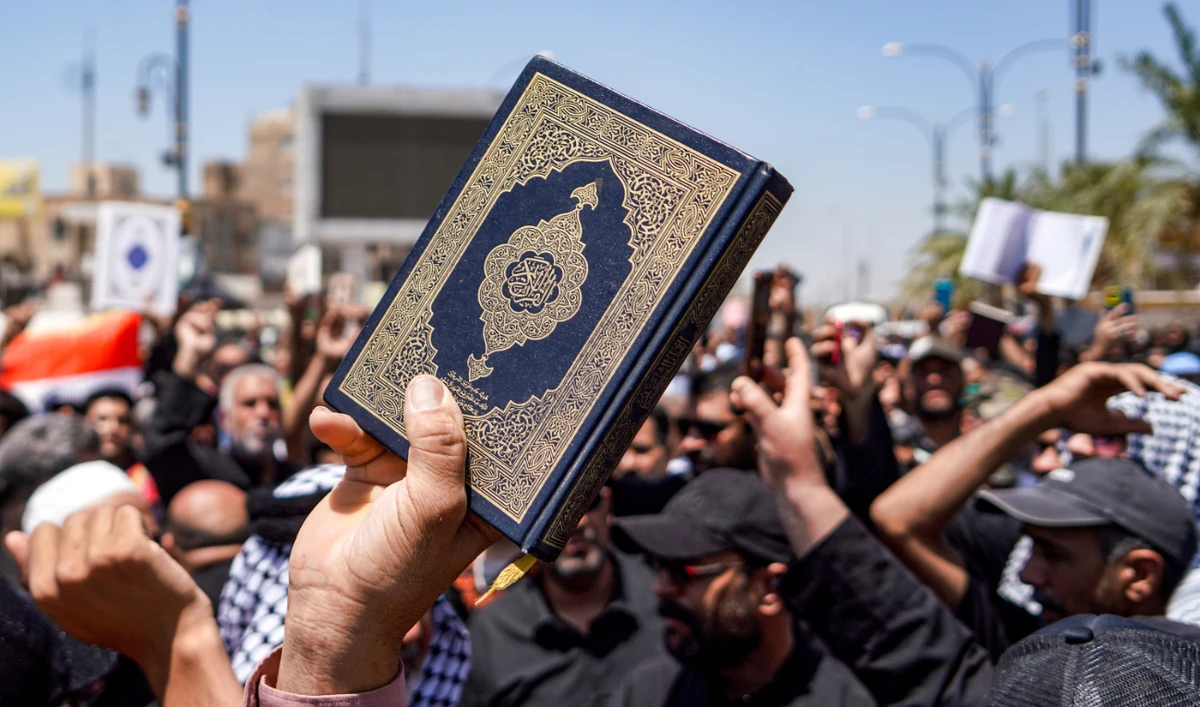 A demonstrator holds a copy of the Holy Qur’an during a rally after the weekly Friday prayers denouncing the burning of the Qur’an in Sweden, in Iraq on July 21, 2023. (AFP)