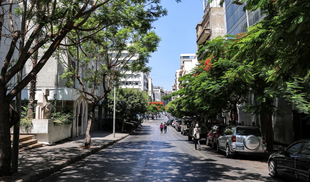 People walk in the shade of trees along central Beirut’s Hamra Street on June 23, 2023. (AFP/File)