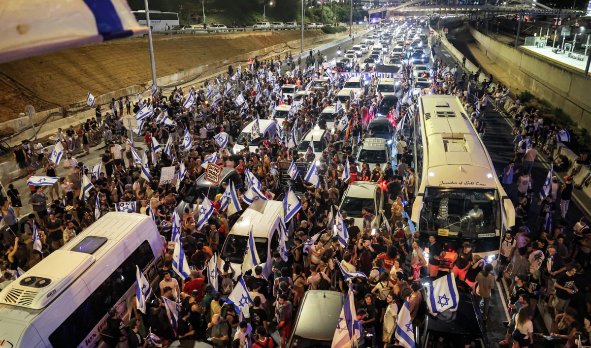 Demonstrators stand between traffic as they block a highway during a protest rally against the Israeli government’s judicial reform plan in Tel Aviv on July 24, 2023. (AFP)