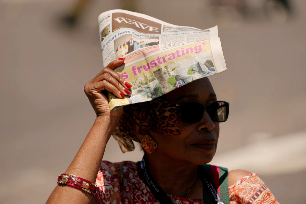 A woman shields herself from the sunlight with a copy of the Los Angeles Wave newspaper, July 15, 2023, in the Leimert Park neighborhood of Los Angeles. (AP)
