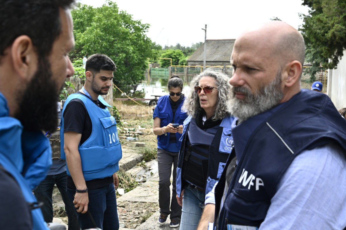 World Food Programe (WFP) Country Director Matthew Hollinghworth (R) and Head of the UN and Humanitarian Coordinator for Ukraine Denise Brown (2nd R), speak to colleagues as they visit a flooded area in the town of Kherson on June 10, 2023, following damage sustained at Kakhovka hydroelectric power plant dam. (AFP)