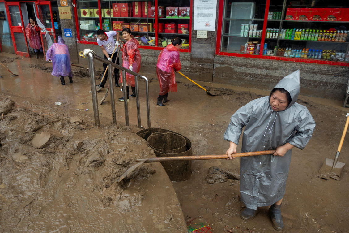 Workers remove mud from a pavement, after flooding caused by days of heavy rain from remnants of Typhoon Doksuri, in Beijing (REUTERS)