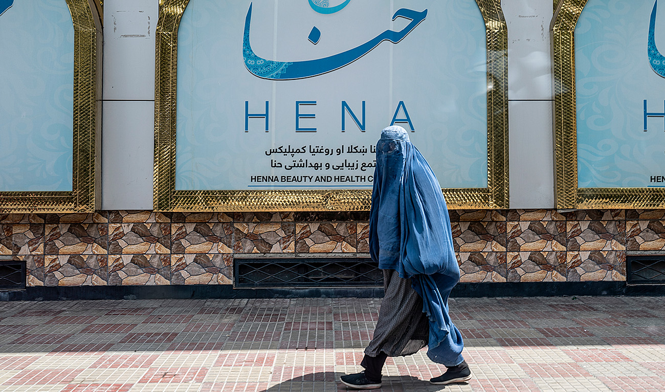 An Afghan burqa-clad woman walks past a beauty salon at the Shahr-e-Naw area in Kabul on July 25, 2023. (AFP/File)