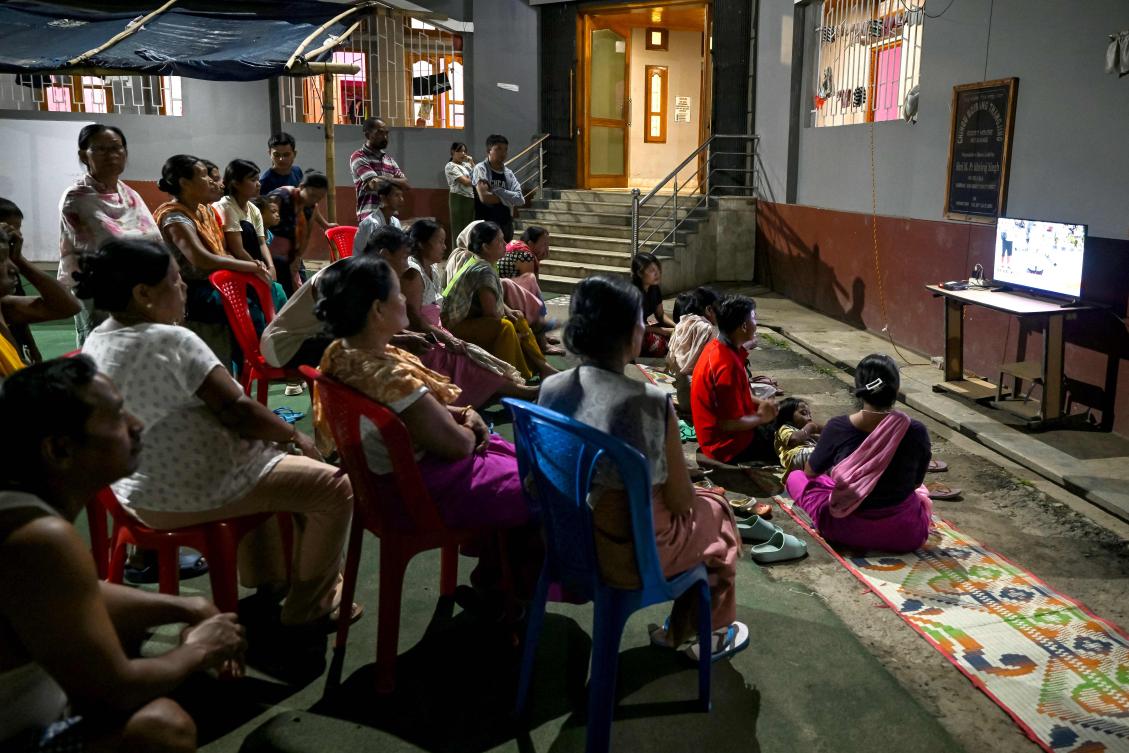 Over 180 people have been killed and thousands have fled their homes since the violence started in Manipur. Above, people watch television in a relief camp for displaced Meitei community. (AFP)