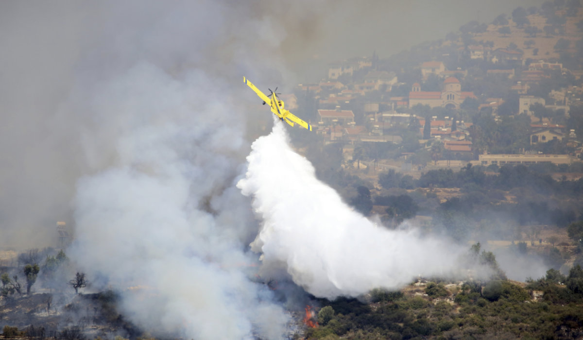 An aircraft drops water over a fire in Apesia, a semi-mountainous village near Limassol, southwestern Cyprus, Monday, Aug. 7, 2023. (AP)