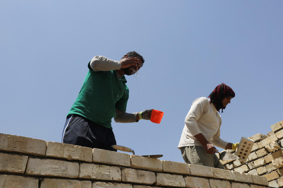 A labourer washes his face to cool off from the scorching summer heat while he works on a building under construction in Baghdad (REUTERS)