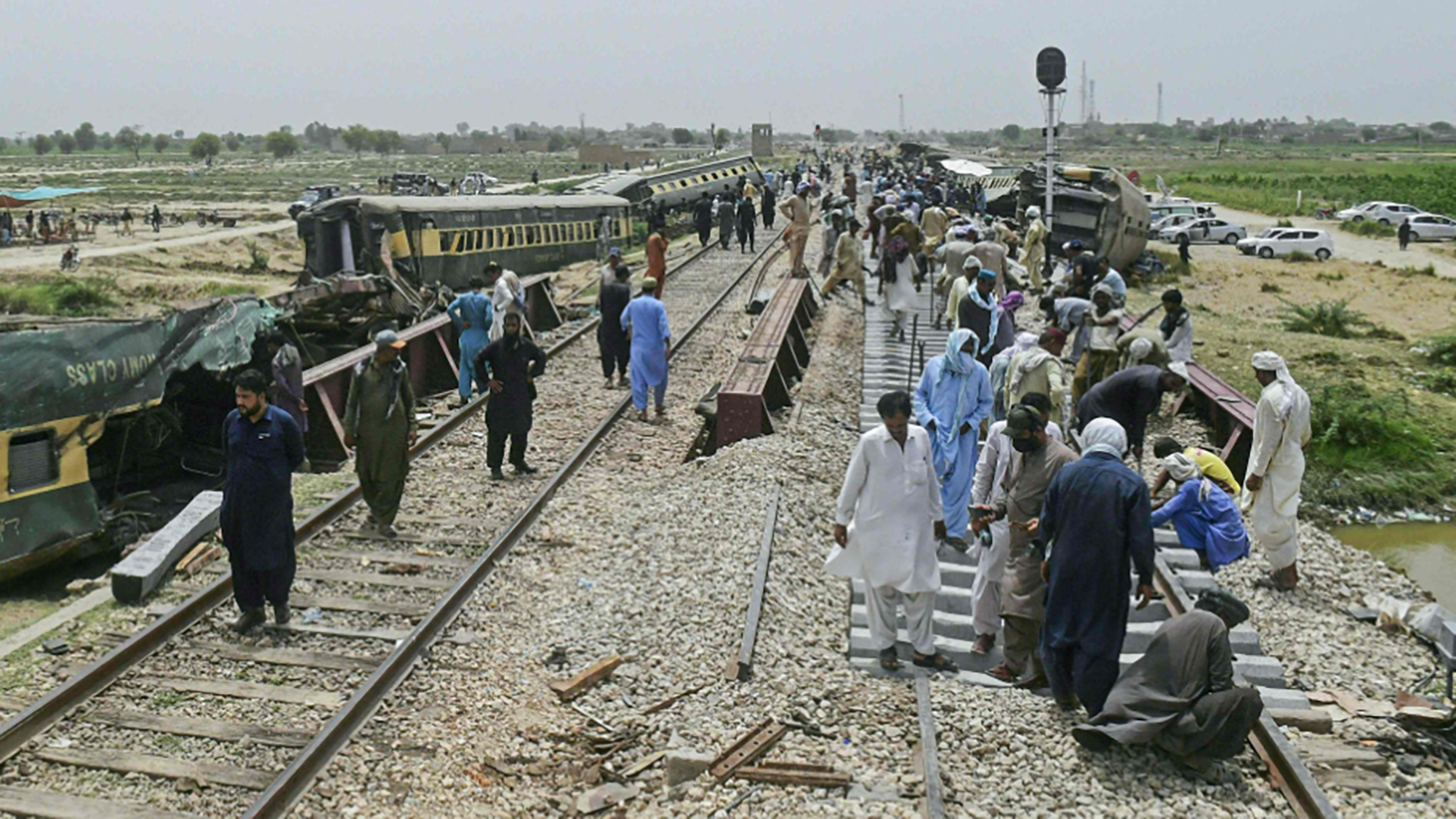 People gather at the accident site, a day after the derailment of a passenger train in Nawabshah on August 7, 2023. (AFP)