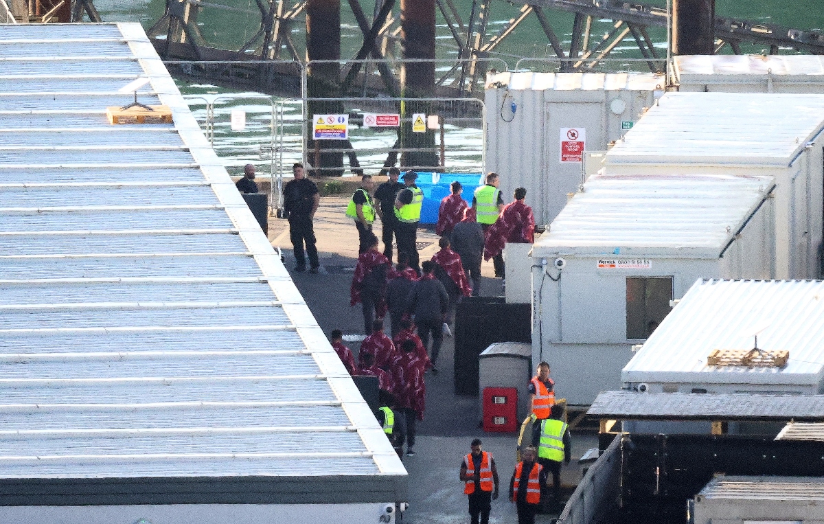 Migrants are escorted by UK Border Force and Interforce officers at the Marina in Dover, southeast England having been picked up at sea while attempting to cross the English Channel from France.(AFP)
