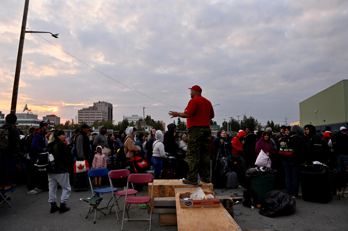 Residents wait outside a local school to get registered for an evacuation flight as wildfires threaten the Northwest Territories town of Yellowknife, Canada on Aug. 17, 2023. (Reuters)