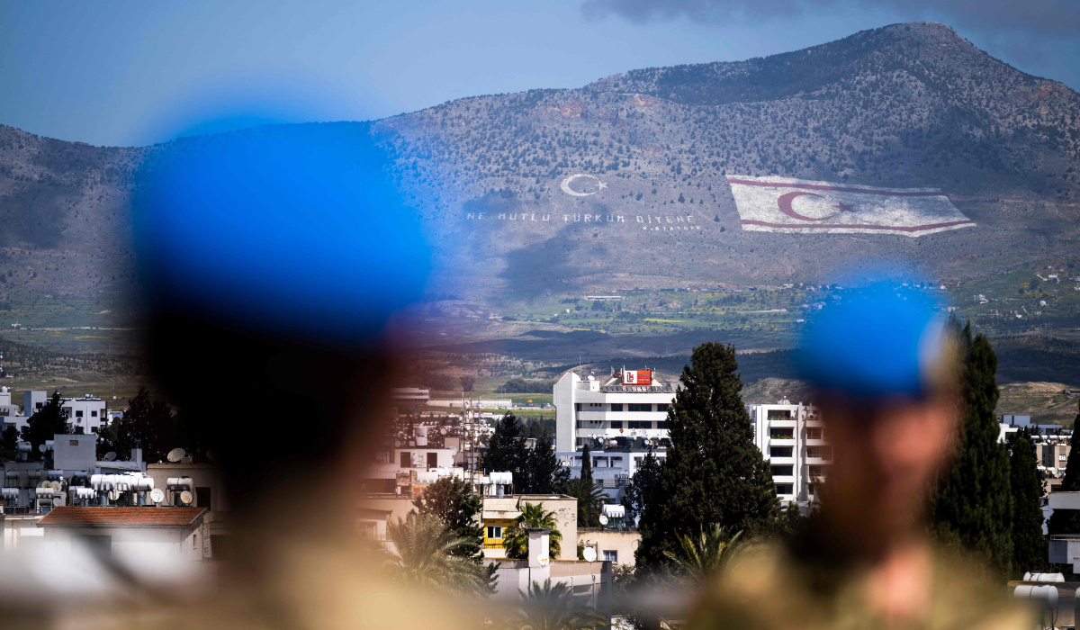 Members of the United Nations Peacekeeping Force in Cyprus (UNFICYP) from the British Household Cavalry Regiment visit the roof of the Ledra Palace in the UN buffer zone separating the divided capital of Nicosia on April 5, 2023, while behind is shown the flag of the self-proclaimed Turkish Republic of Northern Cyprus (TRNC) painted on the island's northern Kyrenia mountain range. (AFP)