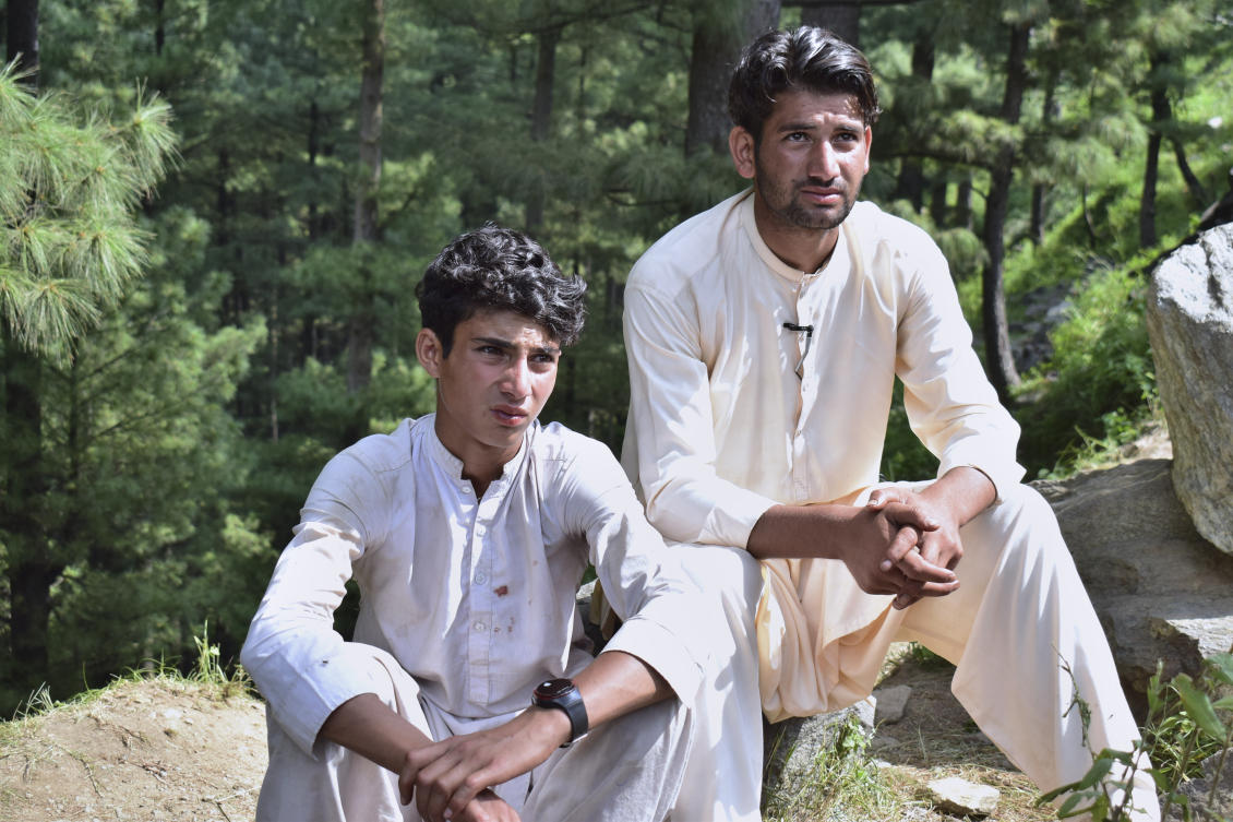 Abrar Ahmed, left, a survivor of cable car incident, sits with his cousin as he talks to members of media, near the incident site, in Pashto village. (AP)