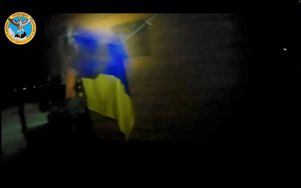A soldier hangs a Ukrainian flag during a 'special operation' by Ukrainian forces at a location given as near Olenivka and Mayak settlements, Crimea, in this screen grab obtained from a handout video released on August 24, 2023. (Ukrainian military/Handout via REUTERS)