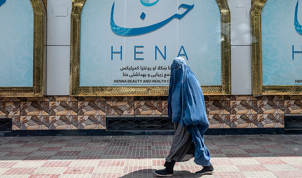 An Afghan burqa-clad woman walks past a beauty salon at the Shahr-e-Naw area in Kabul on July 25, 2023. (AFP/File)