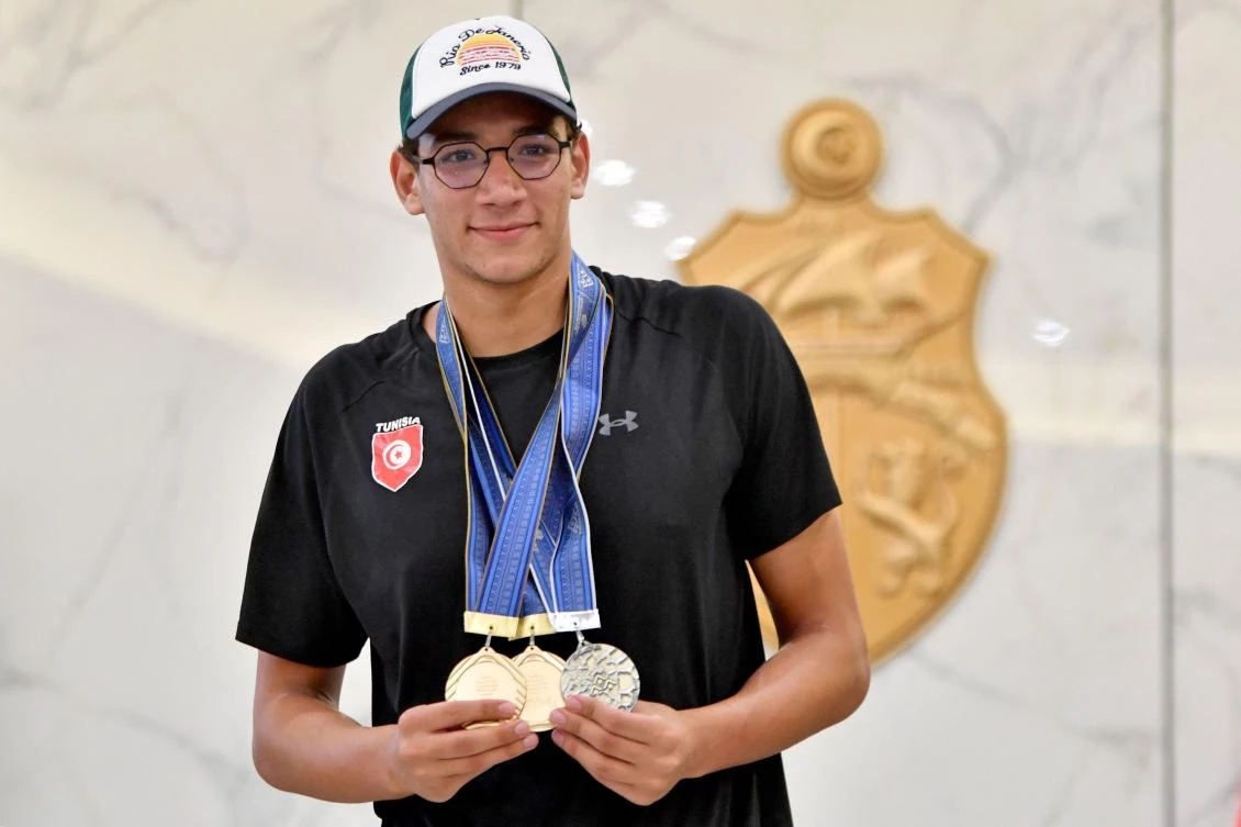 Swimmer Ahmed Hafnaoui of team Tunisia poses with his medals upon arrival in Tunis on August 1, 2023 two days after securing the gold medal in the Men’s 1500m freestyle final during the World Aquatics Championships in Fukuoka. (AFP)