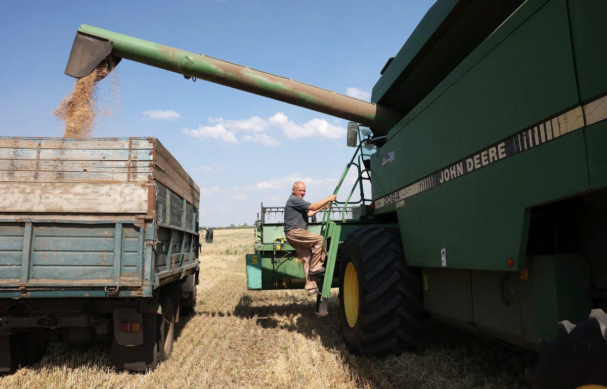 A combine operator climbs aboard a combine as they harvest wheat at a farm near Kramatorsk, in Donetsk region on August 4, 2023, amid the Russian invasion of Ukraine. (AFP)