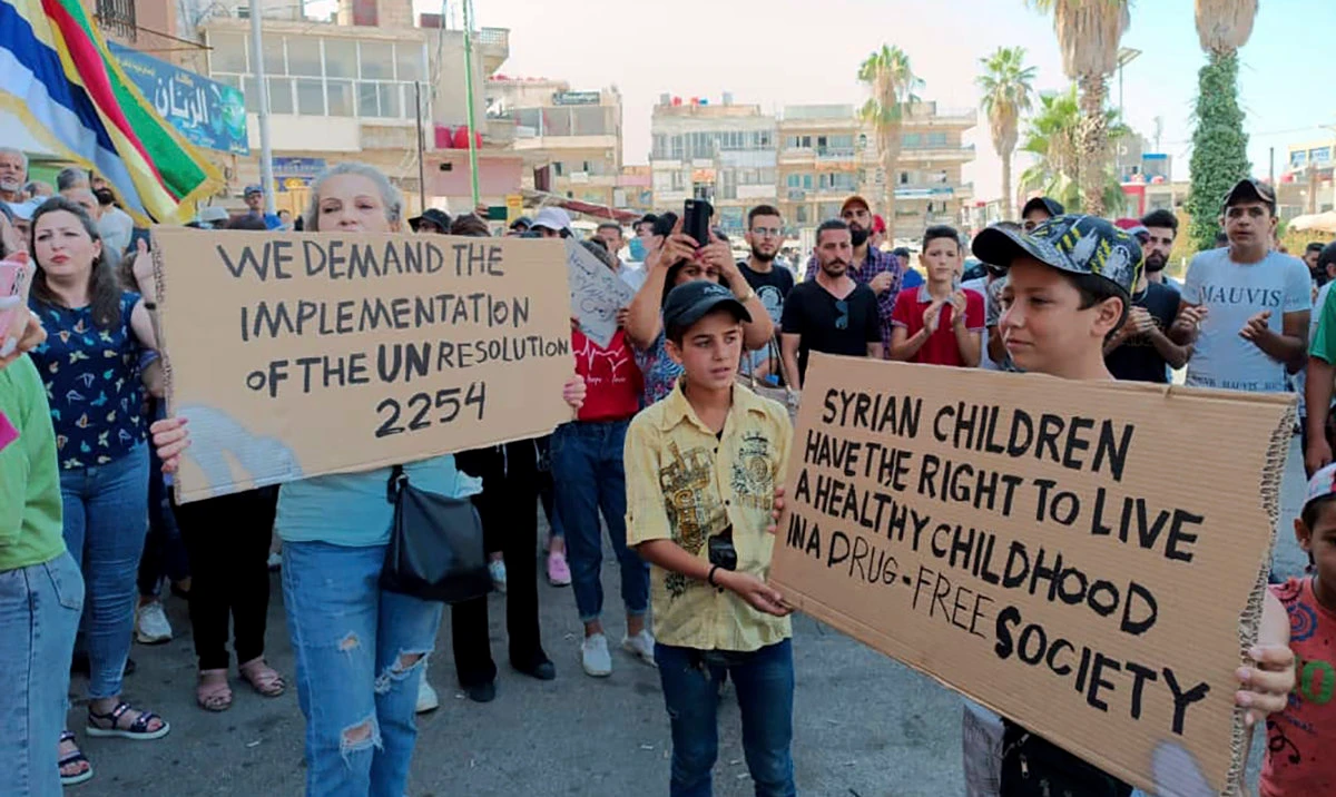 In this photo released by Suwayda24, people hold placards during a protest in the southern city of Sweida, Syria, Saturday, Aug 26, 2023. (AP)