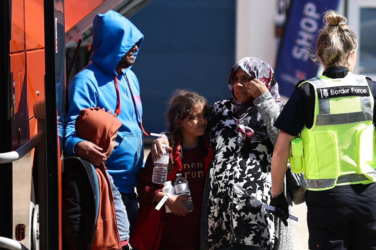 A migrant pregnant woman is helped to board on a bus in order to be taken for processing on the southeast coast of England. (File/AFP)