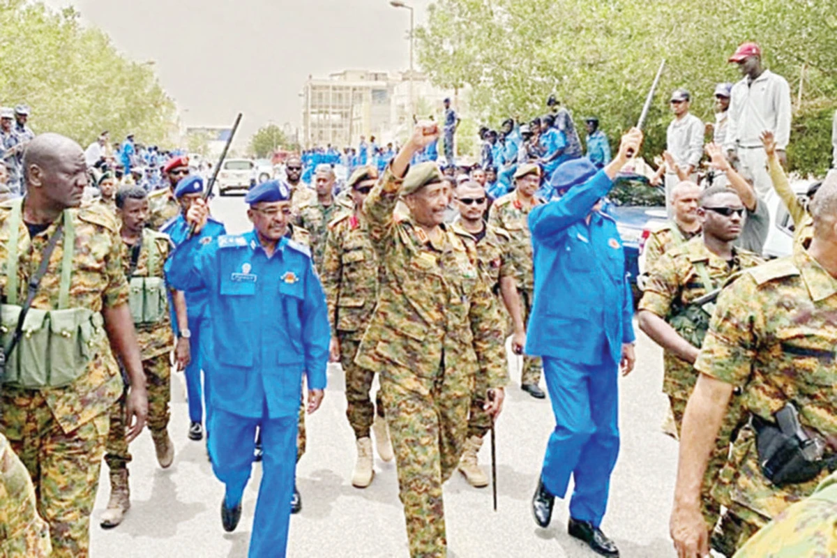 Sudan’s army chief Gen. Abdel Fattah Al-Burhan, flanked by military aides and officers, waves to people during a tour of a neighborhood in Port Sudan. (AFP)