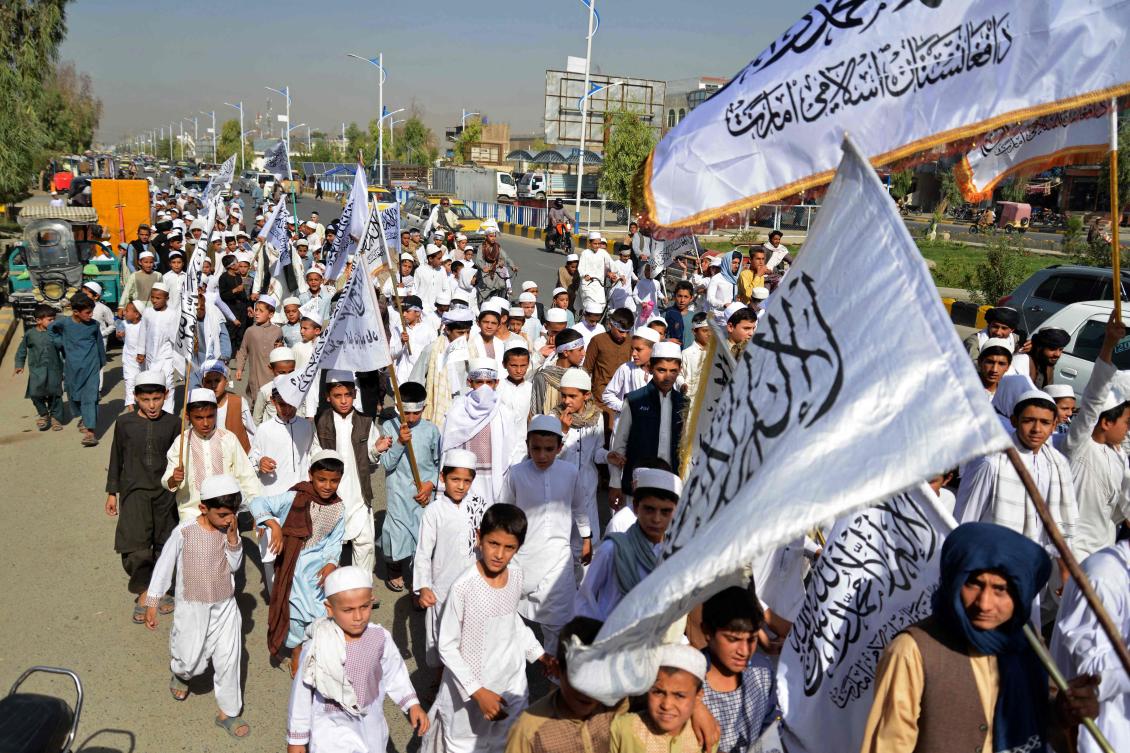 Young boys wave Taliban flags during a procession along a street in Kandahar on August 31, 2023, to celebrate the second anniversary of Taliban’s takeover. (AFP)