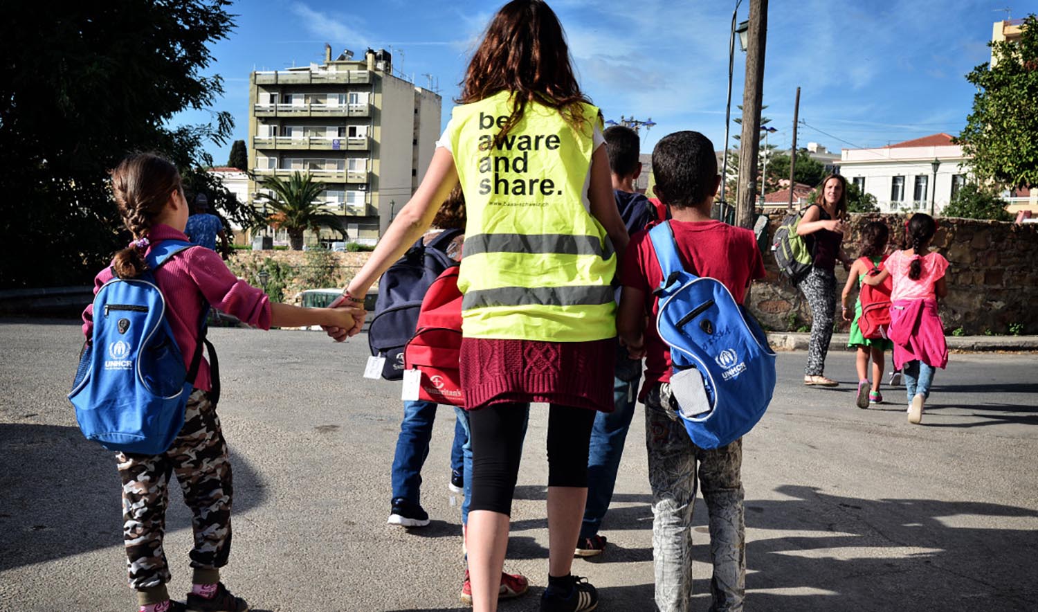 Volunteers walk a group of refugee children towards their school on the island of Chios on October 13, 2016. (AFP/File)