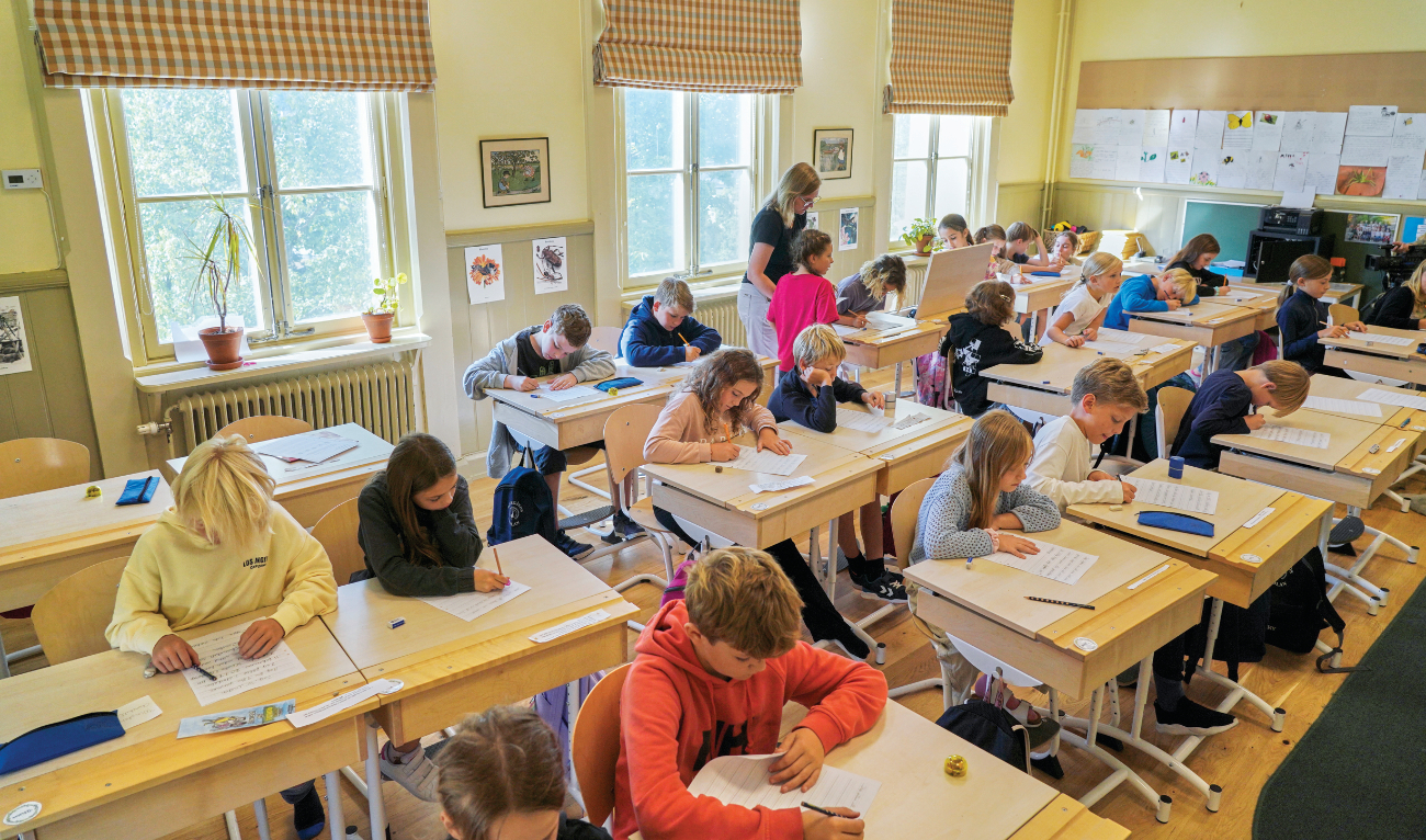 A teacher helps students practice their handwriting at the Djurgardsskolan elementary school in Stockholm, Sweden, on Thursday. (AP)