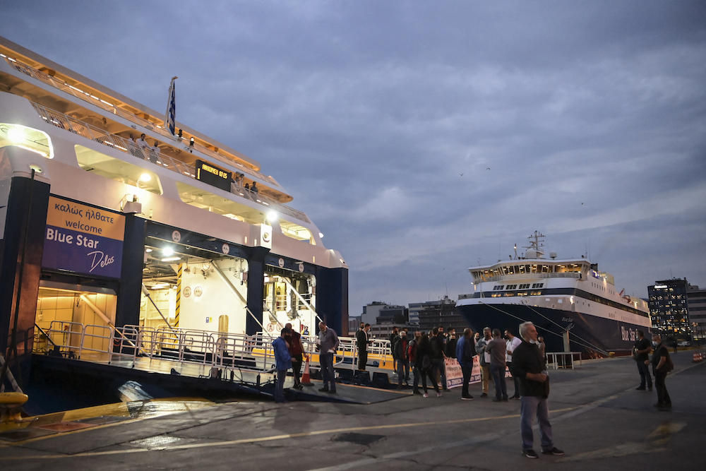 Above, people stand in front of a ferry docked at the main port of Piraeus during a 24-hour general strike on June 10, 2021. (AFP file photo)