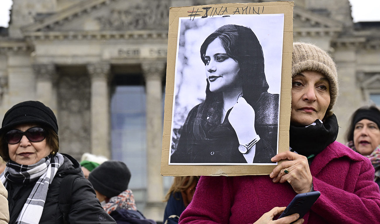 In this file photo, a woman holds a portrait of Mahsa Amini, a young Iranian woman who died after being arrested in Tehran by the Islamic Republic's morality police, during a demonstration in front of the German lower house of parliament, on the occasion of the International Women's Day, on March 8, 2023. (AFP/File)