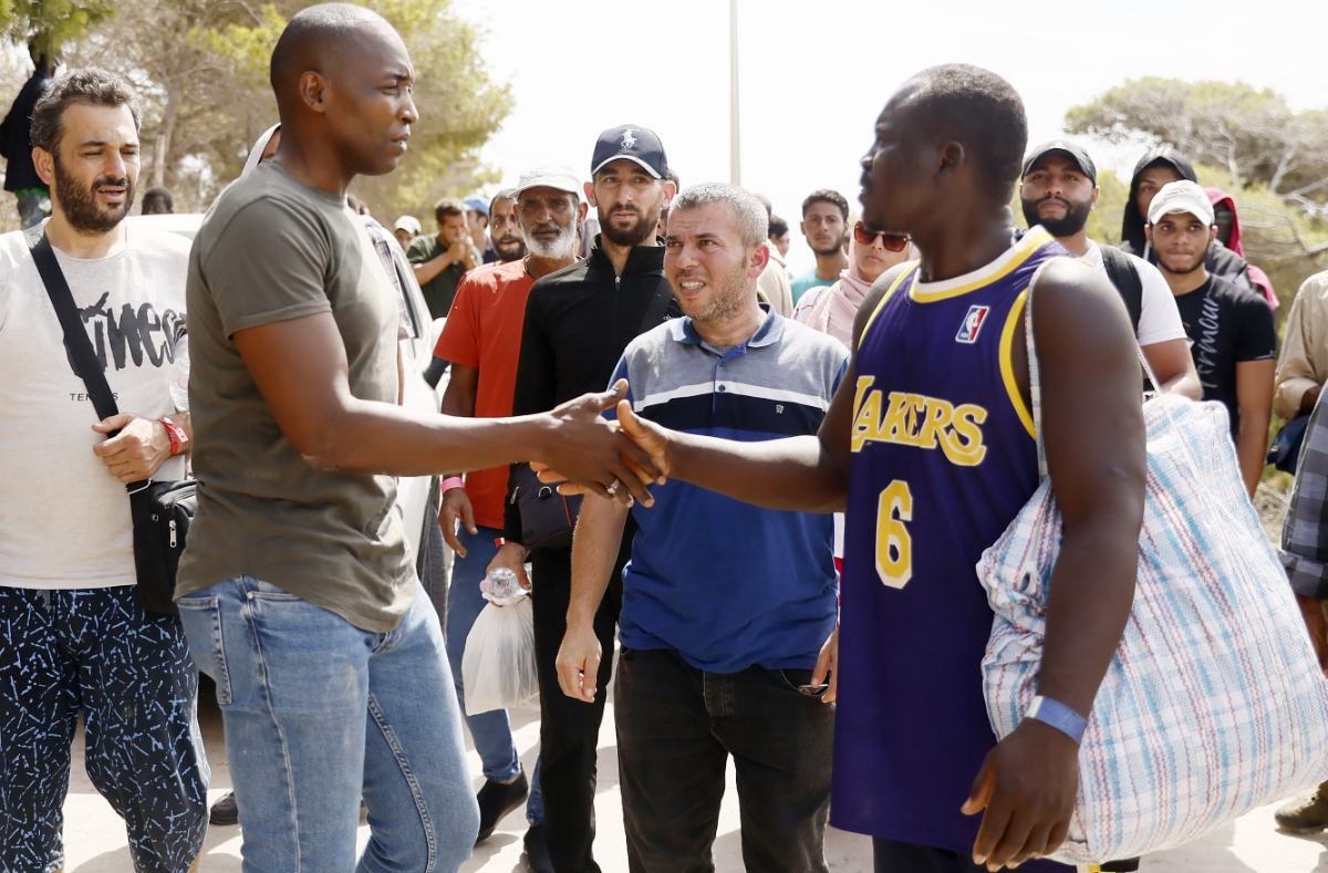 Italian-Ivorian lawmaker Aboubakar Soumahoro, left, speaks to migrants protesting at a reception center on the Sicilian island of Lampedusa, southern Italy, Saturday, Sept. 16, 2023. (AP)
