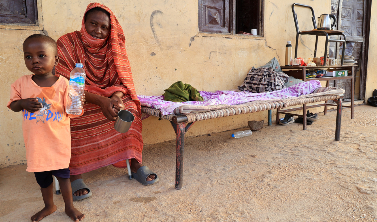 A woman and a child sit outside a classroom at a school that has been transformed into a shelter for people displaced by conflict in Sudan’s northern border town of Wadi Halfa near Egypt on September 11, 2023. (AFP)