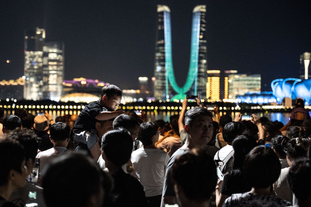 People gather at the promenade of Qiantang River waiting for the light show of the Hangzhou Olympic Sports Centre Stadium (not seen), ahead of the 2022 Asian Games in Hangzhou in China’s eastern Zhejiang province on Tuesday. (AFP)