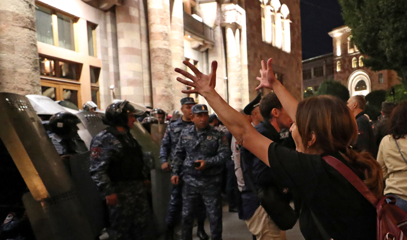 A protester reacts next to law enforcement officers who stand guard outside the government building during a rally to demand the resignation of Armenian Prime Minister following Nagorno-Karabakh surrender, in Yerevan, Armenia, September 21, 2023. (AFP)