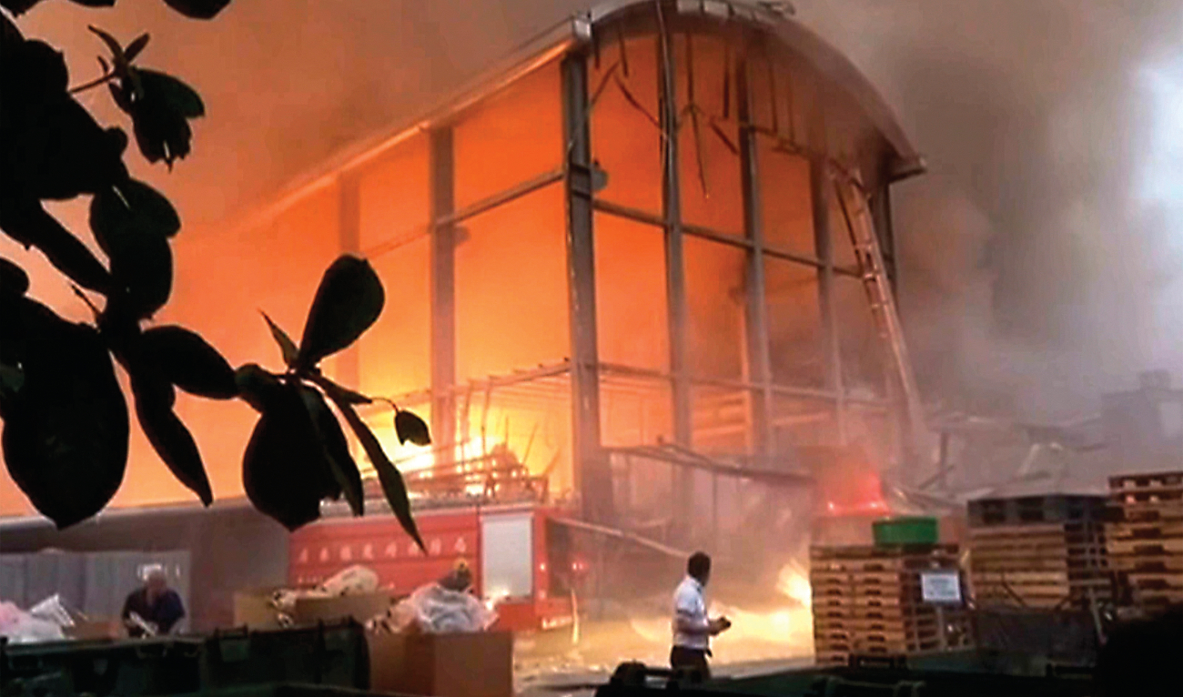 People watch a fire at a factory of golf ball manufacturer Launch Technologies Co. in the southern county of Pingtung in Taiwan on Friday. (AP)