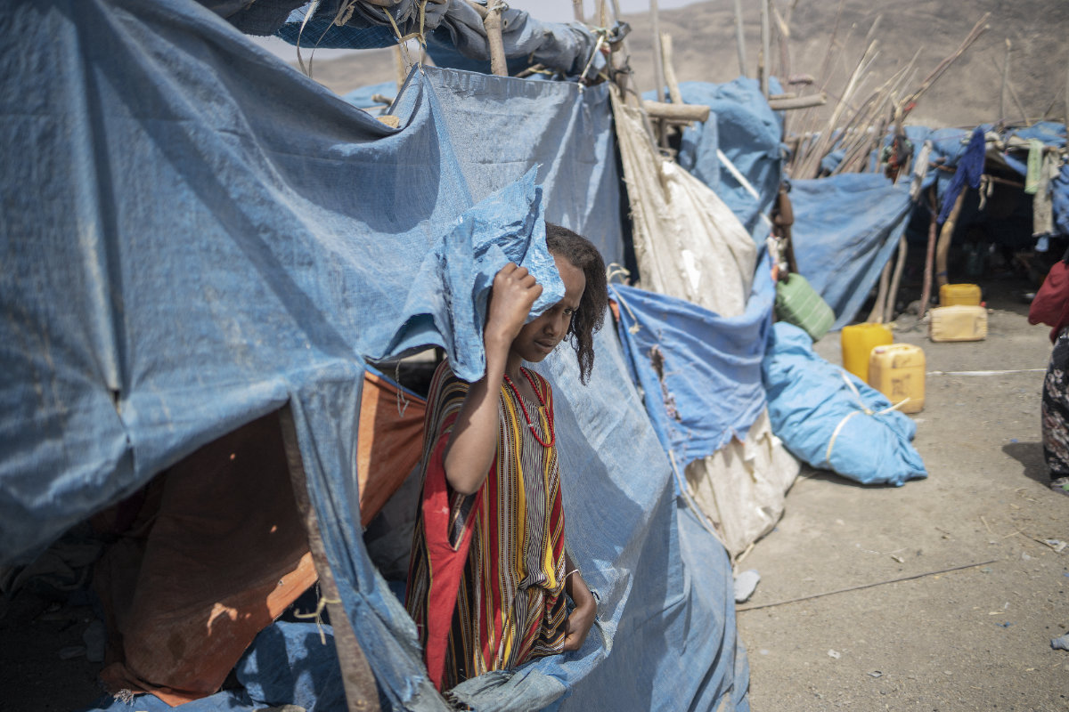 A child peeks from a tent at the internally displaced persons (IDP) camp of Guyah, in Ethiopia's Afar region, on May 17, 2022. More than two million Ethiopians had been displaced in fighting between government troops and Tigray rebels since 2020. (AFP)