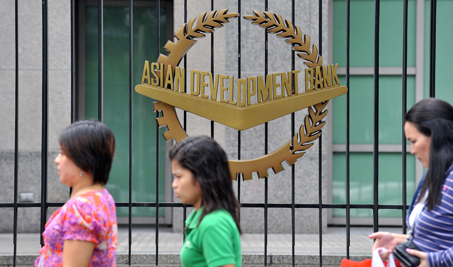 Pedestrians walk past a logo of the Asian Development Bank (ADB) displayed outside its headquarters in Manila, Philippines on September 2, 2010. (AFP/File)