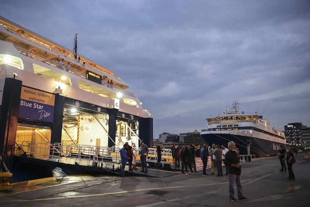 Above, people stand in front of a ferry docked at the main port of Piraeus during a 24-hour general strike on June 10, 2021. (AFP file photo)