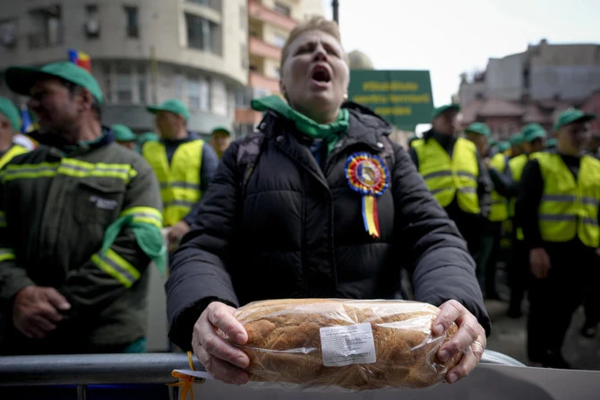 A woman holds a loaf of bread during a farmers' protest in front of the Representative Office of the European Commission in Bucharest on, April 7, 2023 (File/AP)