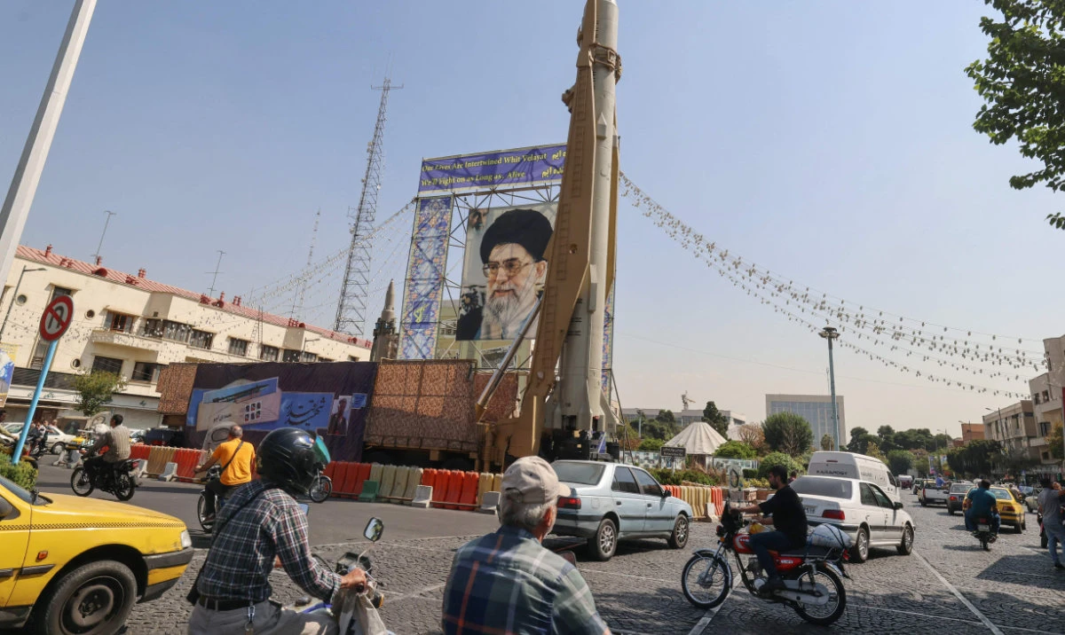 Motorists drive past an Iranian Sejil surface-to-surface missile displayed next to a portrait of the supreme leader, Ayatollah Ali Khamenei. Iranian security forces made dozens of arrests Saturday as protesters commemorated the killing of demonstrators in the region a year ago, human rights groups said. (AFP)