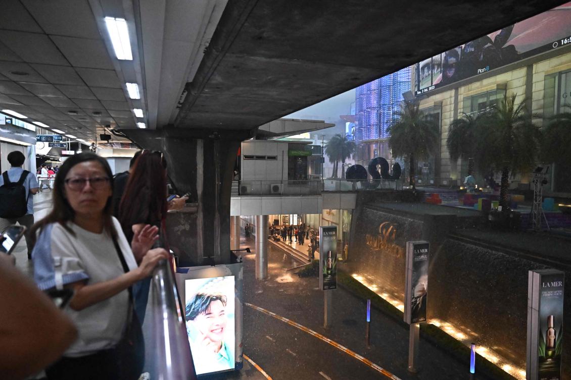 Above, people at a nearby BTS train station look at Siam Paragon shopping center in Bangkok on Oct.3, 2023, after a shooting incident at the mall. (AFP)