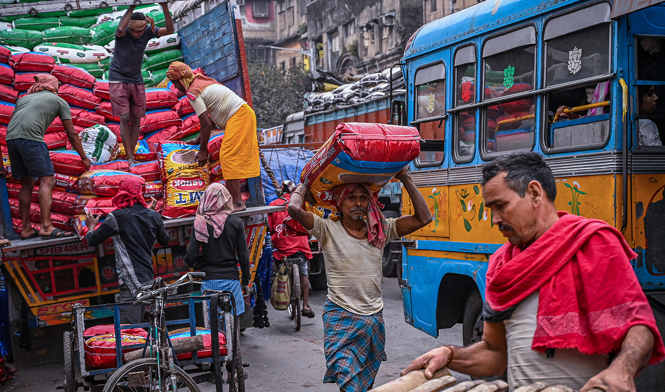 Labours unload sealed sacks of spices at a wholesale market in Kolkata on February 1, 2023. (AFP/File)