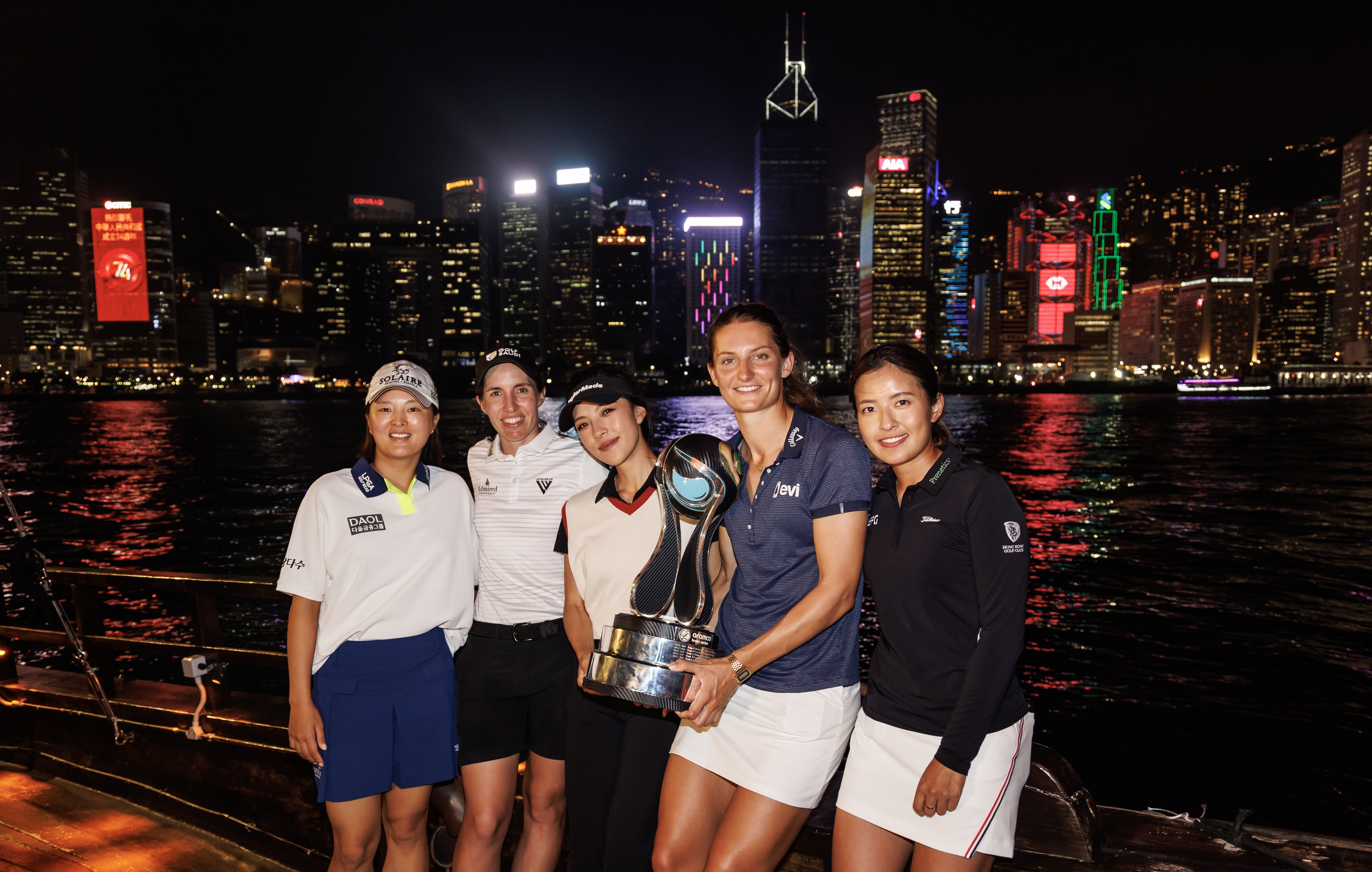(From L to R): Jin Young Ko, Carlota Ciganda, Muni He, Anne van Dam and Tiffany Chan with the Aramco Team Series presented by PIF trophy in front of Hong Kong’s city skyline. (Supplied/ATS presented by PIF)