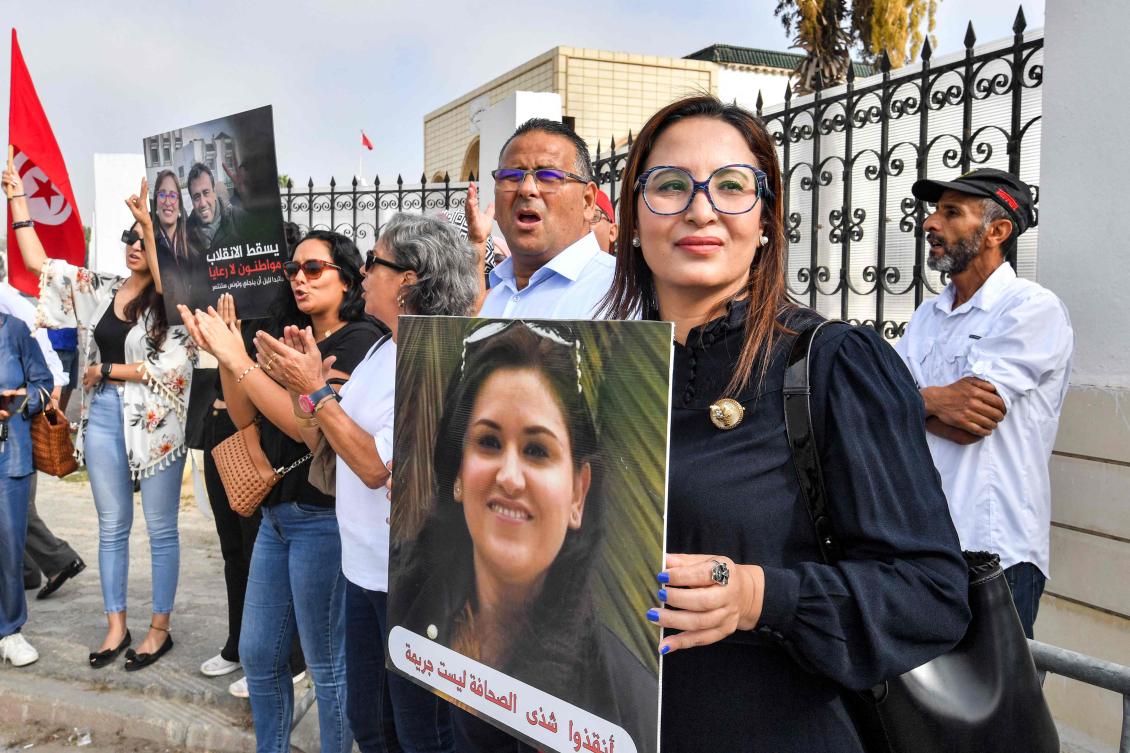 Chaima Issa (R), member of Tunisia's "National Salvation Front" opposition coalition, holds a picture of jailed journalist Chadha Hadj Mbarek as she arrives outside a military court in Tunis. Issa had been freed from jail late on July 13 after spending more than five months in custody. The Tunisian writer was arrested in February along with former minister and lawyer Lazhar Akremi on charges of "conspiracy against state security".(AFP)
