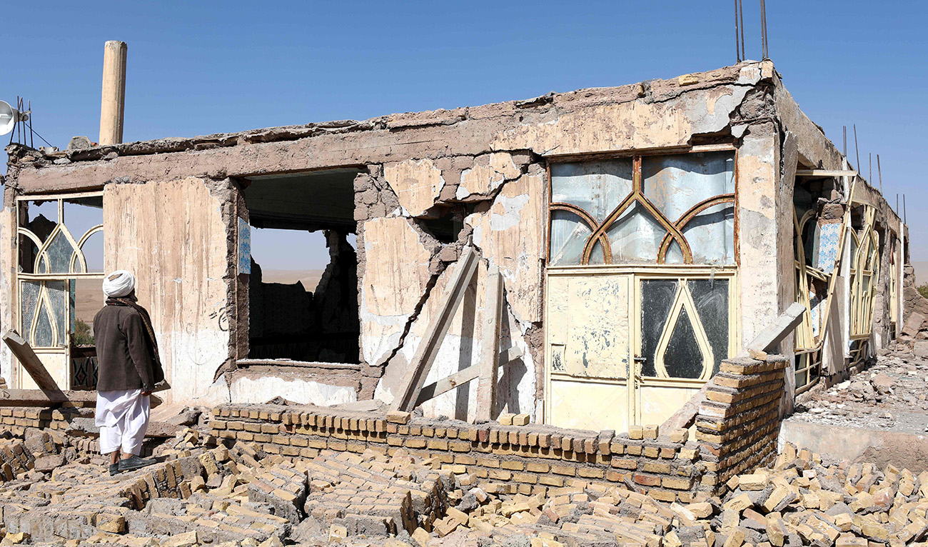 An Afghan man stands near a damaged house after the earthquakes in Sarbuland village, Zendeh Jan district of Herat province on October 8, 2023. (AFP)