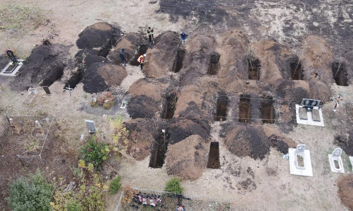 An aerial photograph taken with a drone shows workers digging graves for the victims of an airstrike earlier in the month, at the cemetery in the Groza village, Kharkiv region, on October 9, 2023, amid the Russian invasion of Ukraine. (File/AFP)