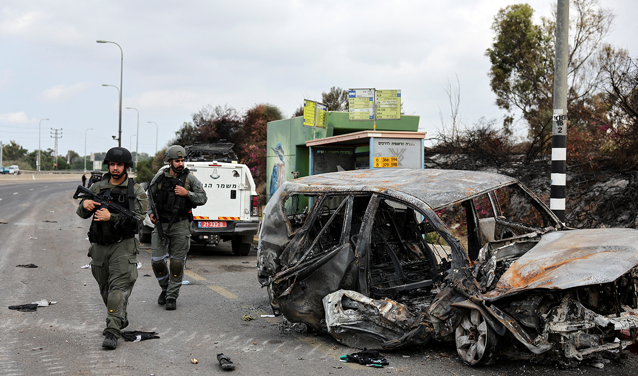 Israeli border police walk past a burnt out car as rockets are launched from the Gaza Strip towards Israel, in Ashkelon, southern Israel October 10, 2023. (Reuters)