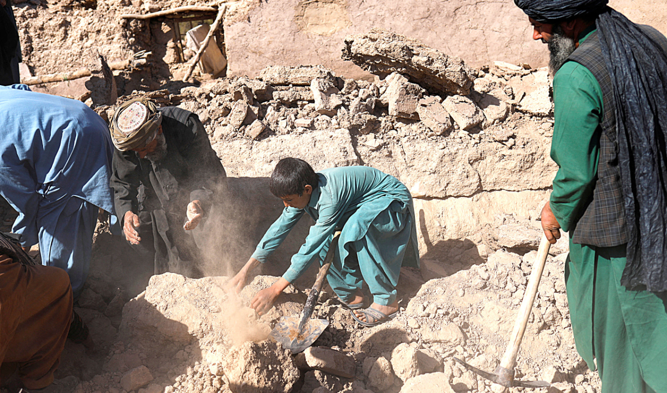 An Afghan child removes debris from his damaged house after the recent earthquake in the district of Zinda Jan, in Herat. (Reuters)