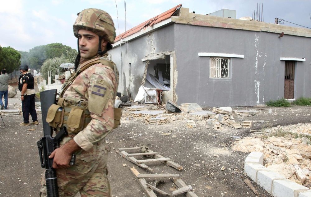 A soldier stands guard outside a house shelled by Israeli forces on the outskirts of the southern Lebanese border village of Dhaira on October 11, 2023. (AFP)
